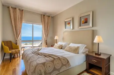 a bedroom with a bed with a view of the ocean at Stylish apartment with balcony and amazing views over Funchal and the sea in Funchal