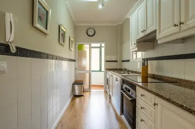 a kitchen with white cabinets and a clock on the wall at Stylish apartment with balcony and amazing views over Funchal and the sea in Funchal