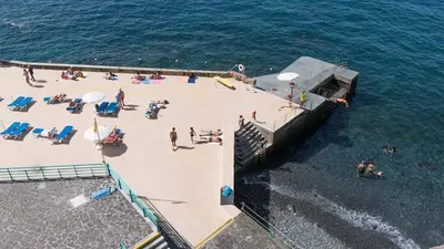 a group of people on a beach near the water at Stylish apartment with balcony and amazing views over Funchal and the sea in Funchal