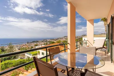 a balcony with a table and chairs and a view of the ocean at Stylish apartment with balcony and amazing views over Funchal and the sea in Funchal