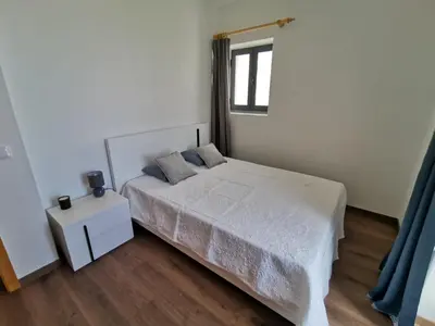 a white bedroom with a bed and a window at Lucas House in Ponta do Sol