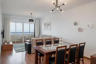 a dining room and living room with a table and chairs at Garajau III by An Island Apart in Caniço