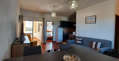 a kitchen and a living room with a table and chairs at Arrifana View Flat - 2km Praia Arrifana in Aljezur
