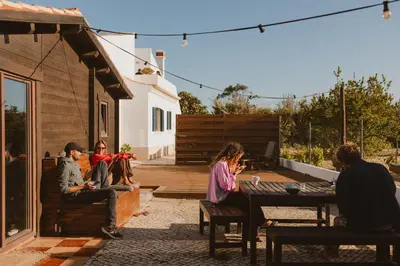 a woman in the water with her hands in the air at Aldeia Caiçara Surf House in Sagres