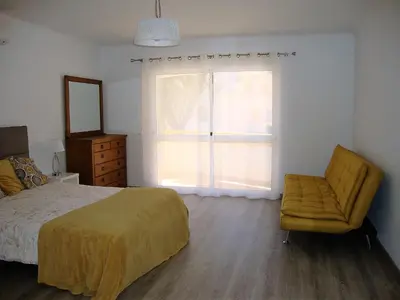 a bedroom with a bed and a chair and a window at Belinha Guest House in Luz