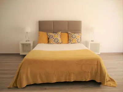 a bedroom with a large bed with yellow sheets and pillows at Belinha Guest House in Luz