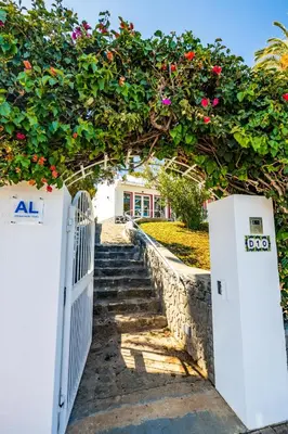 a gate with a hedge of flowers over a stone wall at Casa Maravilha II in Caniço