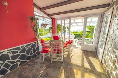 a dining room with a red wall and chairs at Casa Maravilha II in Caniço