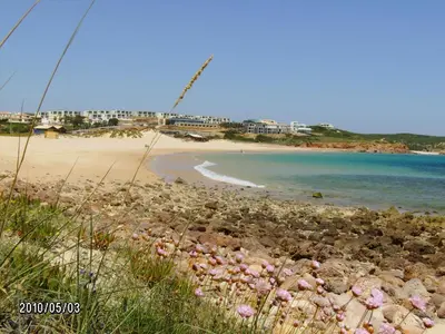 a straw umbrella sitting on the beach at Apartamento Mahalo in Sagres