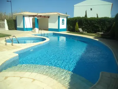 a swimming pool with blue water in front of a house at Apartamento Mahalo in Sagres