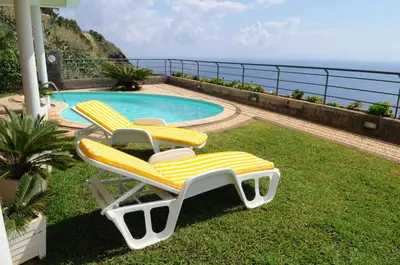 two lounge chairs and a swimming pool with the ocean at An uninterrupted 180 overlooking the Atlantic Ocean in Caniço