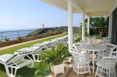 a row of white chairs and tables on a porch at An uninterrupted 180 overlooking the Atlantic Ocean in Caniço