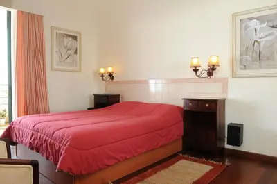 a bedroom with a red bed with a red blanket at An uninterrupted 180 overlooking the Atlantic Ocean in Caniço