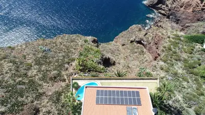 a house with a solar panel on the side of a mountain at An uninterrupted 180 overlooking the Atlantic Ocean in Caniço