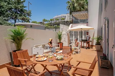 a group of people sitting around a table on a patio at Grand Residence I by An Island Apart in Funchal