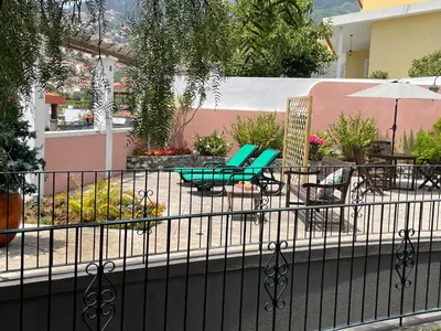 a patio with chairs and tables and an umbrella at Studio by Casa da Quinta in Funchal