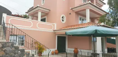 a pink house with a green umbrella in front of it at Studio by Casa da Quinta in Funchal