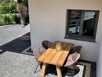 a wooden table and chairs sitting next to a building at Calheta Boutique Houses in Arco da Calheta