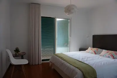 a bedroom with a bed and a chair and a window at Freda House in Funchal