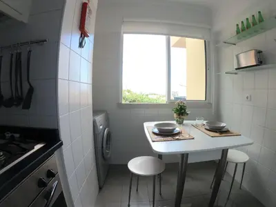 a small white kitchen with a table and two stools at Freda House in Funchal