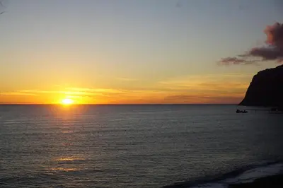 a sunset over the ocean with the sun setting at Freda House in Funchal