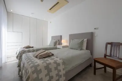 two beds in a bedroom with a chair and a table at Bela Vista da Luz 17 by Destination Algarve in Luz