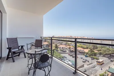 a balcony with chairs and a table and a view of a city at Elegant Apartment with Sea Views by Trip2Portugal in Funchal