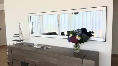 a vase of flowers on a dresser with a mirror at Ponte House in Porto Moniz