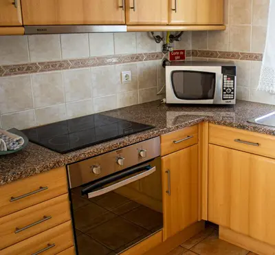 a kitchen with a stove top oven next to a microwave at Casa do Mar in Salema