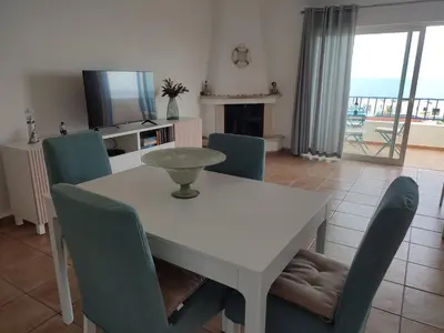 a dining room with a white table and chairs at Casa do Mar in Salema