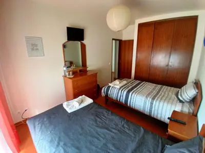 a bedroom with two beds and a table and a window at CASA DIAS in Vila do Bispo