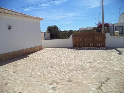 a brick patio with a fence and a wooden gate at Casa Pinheirinho in Sagres
