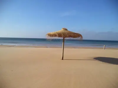 a straw umbrella sitting on the beach at Casa Pinheirinho in Sagres