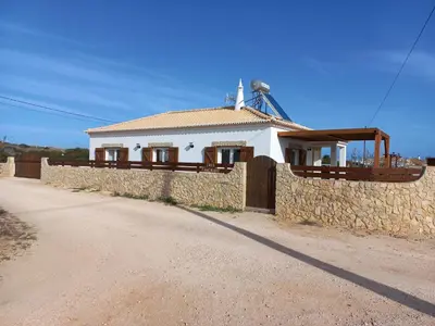 a white house with a stone wall and a fence at Casa Pinheirinho in Sagres