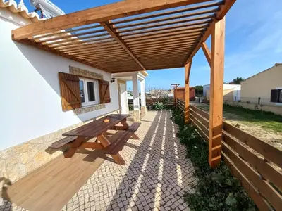 a wooden pergola with a bench on a patio at Casa Pinheirinho in Sagres