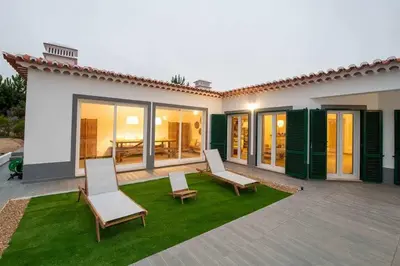 a house with two chairs and a patio with grass at Az Villa Sea e Sun in Aljezur
