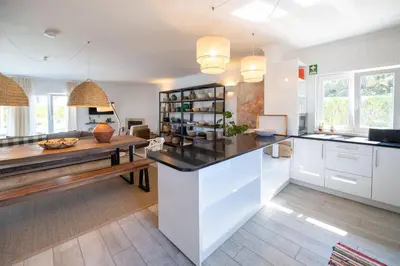 a kitchen with white cabinets and a wooden table at Az Villa Sea e Sun in Aljezur