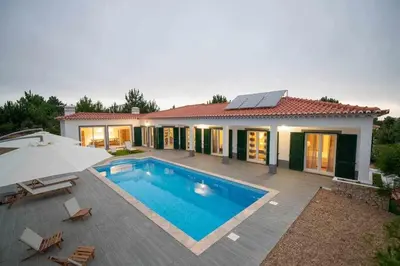 a house with a swimming pool and an umbrella at Az Villa Sea e Sun in Aljezur