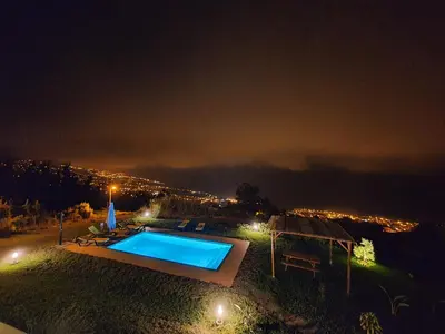 a swimming pool at night with a city at Calheta Glamping Pods - Nature Retreat in Calheta