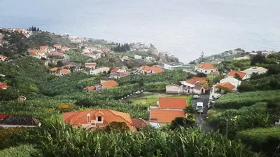 a village on a hill with houses and the ocean at Apartamentos Villa in Ponta do Sol
