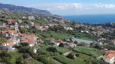 a village on a hill with houses and the ocean at Apartamentos Villa in Ponta do Sol
