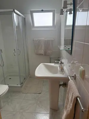 a white bathroom with a shower and a sink at VILLA FELICIDADE in Arco da Calheta