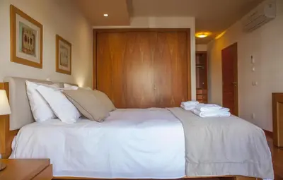 a bedroom with a white bed with a wooden wall at B27 - LuzBay 2 Bed Apartment in Luz