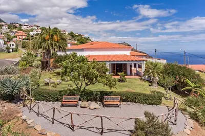 a house with two benches in front of a yard at Southern Sunny House by An Island Apart in Calheta
