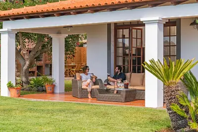 two people sitting on a patio in front of a house at Southern Sunny House by An Island Apart in Calheta