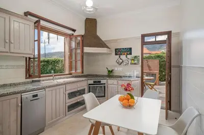 a kitchen with a table with a bowl of fruit on it at Southern Sunny House by An Island Apart in Calheta