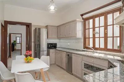 a kitchen with wooden cabinets and a white table at Southern Sunny House by An Island Apart in Calheta