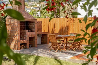 a backyard patio with a table and a fireplace at Southern Sunny House by An Island Apart in Calheta