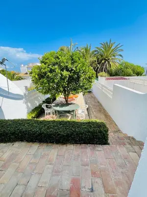 two lounge chairs under a tree in a garden at 38, Vila Gaivota in Luz