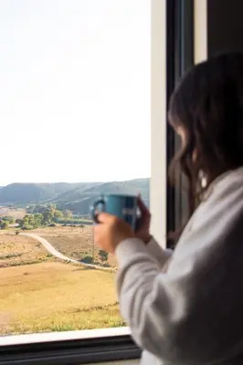 a woman taking a picture of a field from a window at Casa Bombordo in Carrapateira